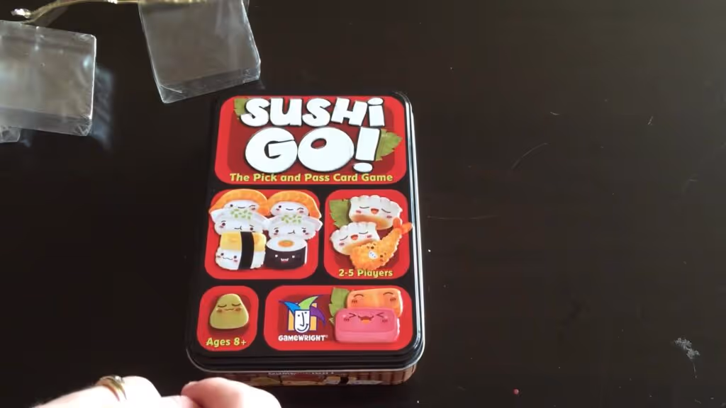 Sushi Go card game tin box with colorful sushi illustrations.
